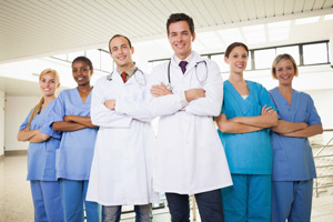 Picture of two male Physicians and four females Nurses standing next to one another with their arms crossed while smiling.