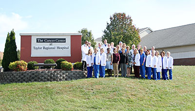 Picture of The Cancer Care Staff standing outside of The Taylor Regional Hospital in front of The Cancer Center sign.