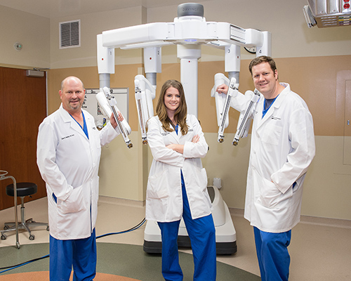 TRH Robotic Surgery Team:
Dr. James Watkins, Dr. Meredith Angel and Dr. Ben AngelPicture of one female and two male surgeon's standing in front of and to the side of The Robotic Robotic Surgery with the daVinci Robotic Surgery with the daVinci Xi™ Surgical System
The da Vinci surgical system helps enable your surgeon to perform minimally-invasive surgery with an advanced set of instruments and a 3D high-definition view of the surgical area. Minimally invasive surgery with daVinci is widely used in general surgery, urology and gynecology procedures.